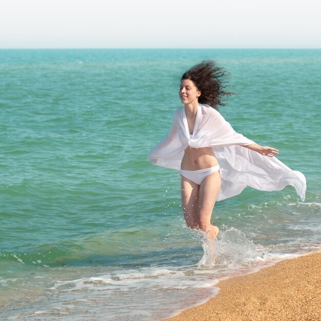 Młoda szczęśliwa kobieta biegająca po plaży