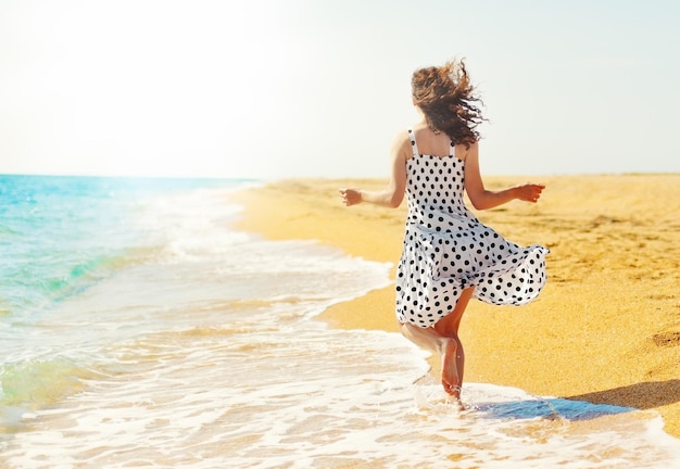 Młoda szczęśliwa kobieta biegająca po plaży