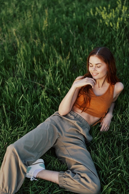 Młoda szczęśliwa kobieta leżąca zrelaksowana na trawie w parku styl życia szczęśliwej osoby bez depresji