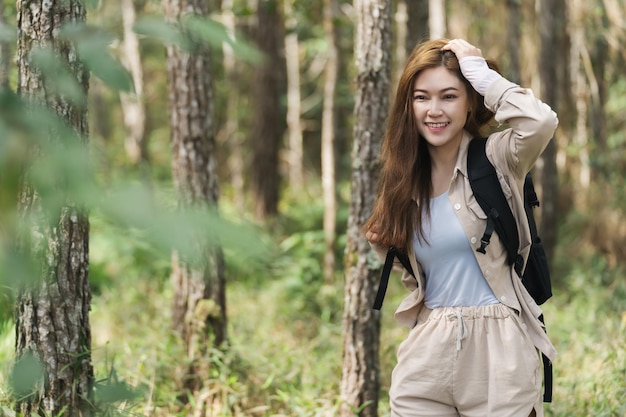 Młoda szczęśliwa kobieta niosąca plecak podróżuje po lesie
