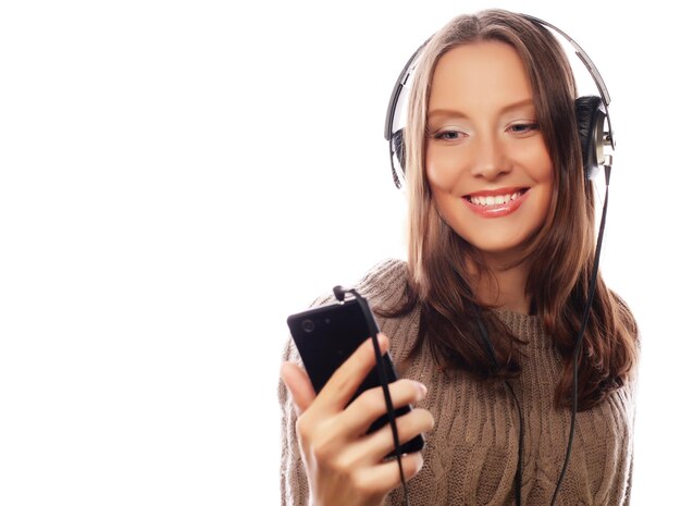 Młoda szczęśliwa kobieta słucha muzyki ze słuchawkami na białym tle