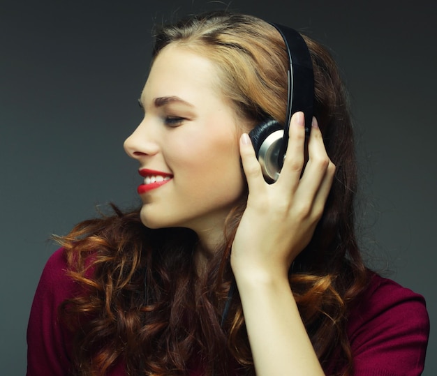 Młoda szczęśliwa kobieta słuchająca muzyki ze słuchawkami