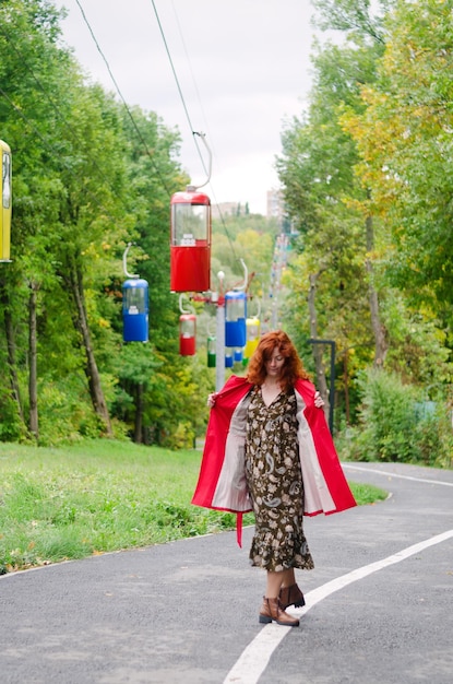 Młoda szczęśliwa kobieta, studentka o rudych włosach, piegach, niebieskich oczach w berecie, chodzący płaszcz. jesienny park