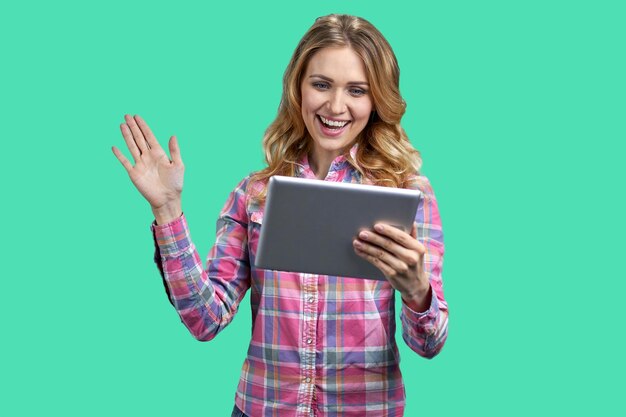Młoda szczęśliwa kobieta trzymająca cyfrowy tablet i machająca ręką młoda radosna kobieta prowadząca rozmowę wideo