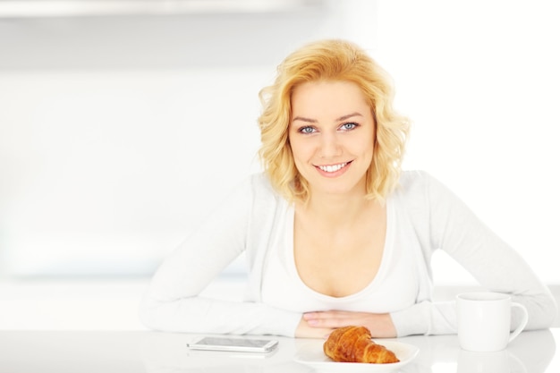 młoda szczęśliwa kobieta używająca smartfona w kuchni