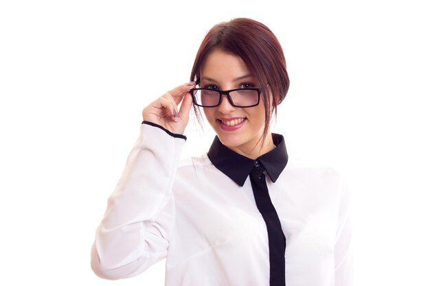 Młoda szczęśliwa kobieta w biało-czarnej koszuli z czarnymi okularami na białym tle w studio