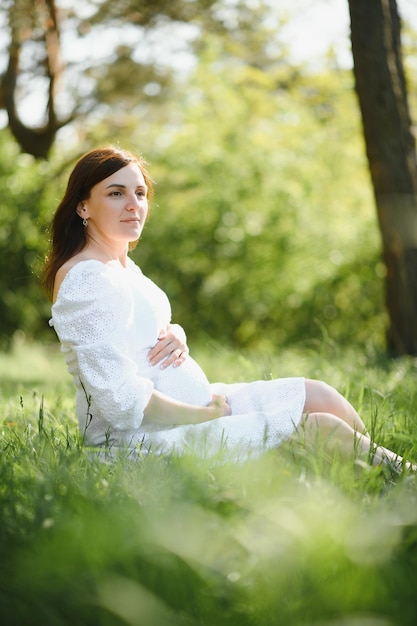 Młoda szczęśliwa kobieta w ciąży relaksuje i cieszy się życiem na łonie natury Zdjęcie na zewnątrz