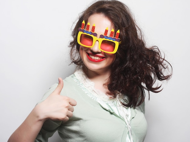 Młoda szczęśliwa kobieta z dużymi pomarańczowymi okularami przeciwsłonecznymi, gotowa na imprezę