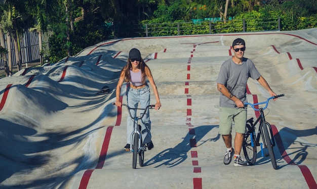Młoda szczęśliwa para lubi jeździć na bmxie w skateparku
