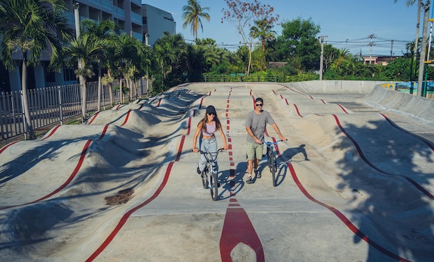 Młoda szczęśliwa para lubi jeździć na bmxie w skateparku