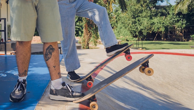 Zdjęcie młoda szczęśliwa para z deskorolkami cieszy się longboardem w skateparku