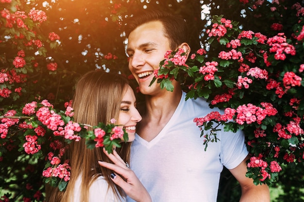 Młoda szczęśliwa para zakochanych na zewnątrz. kochający mężczyzna i kobieta na spacerze w kwitnącym wiosną parku