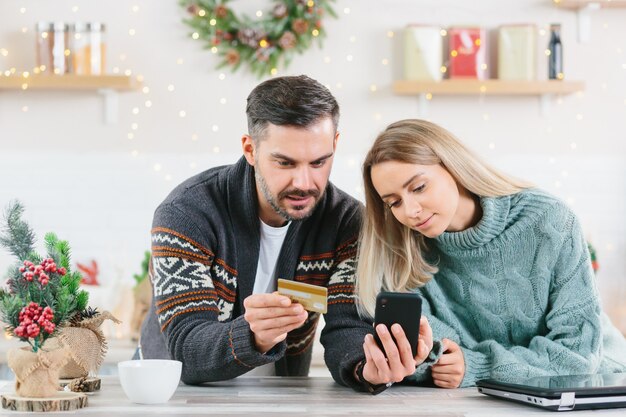 Młoda Szczęśliwa Rodzina Podczas świąt Sylwestrowych I świąt W Domu Radośnie Kupuj Prezenty Online Za Pomocą Smartfona I Karty Kredytowej