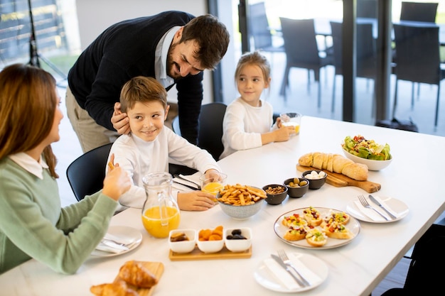 Młoda szczęśliwa rodzina rozmawia podczas śniadania przy stole w mieszkaniu
