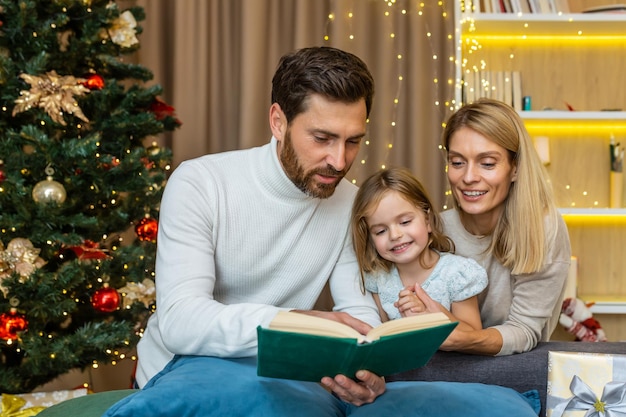 Młoda szczęśliwa rodzina spędza razem czas w wigilię mama i tata czytają im książkę