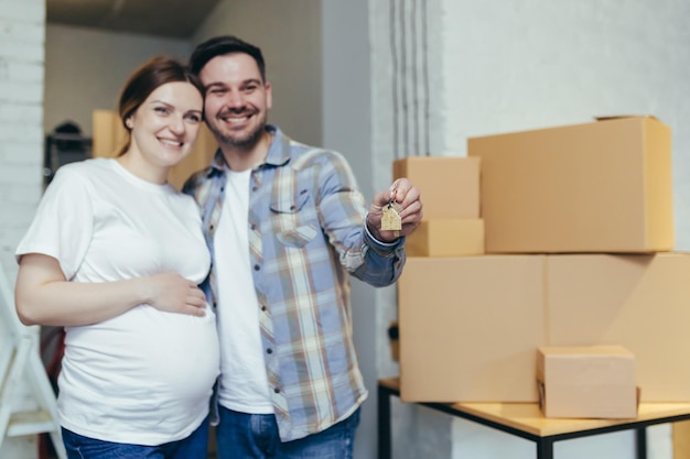 Młoda szczęśliwa rodzina spodziewa się dziecka Kobieta w ciąży i mąż przeprowadzili się do nowego mieszkania Rozpakuj pudełka z rzeczami Przytulanie uśmiechnięte