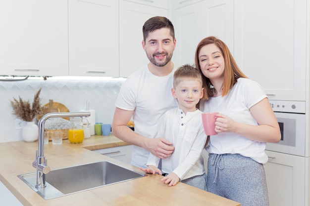 Młoda szczęśliwa rodzina z dwoma młodymi synami razem przygotowywanie śniadania w kuchni