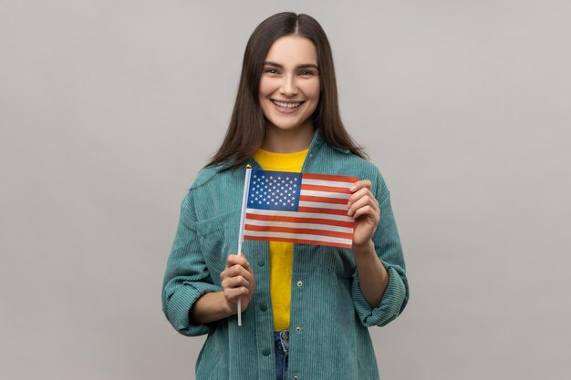 Młoda szczęśliwa zadowolona kobieta stojąca i trzymająca amerykańską flagę z okazji święta narodowego