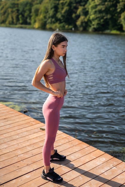 Młoda szczupła kobieta noszenie odzieży sportowej odpoczynku po porannych ćwiczeniach w pobliżu jeziora. pojęcie zdrowego stylu życia