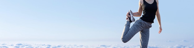 Młoda szczupła wysportowana dziewczyna w stroju sportowym wykonuje zestaw ćwiczeń Sprawność fizyczna i zdrowy styl życia na tle chmur nieba