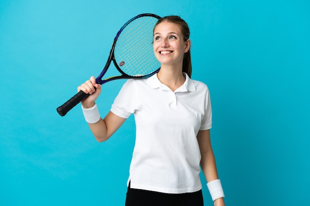 Młoda tenisistka kobieta na niebieskim tle myślenia pomysł, patrząc w górę