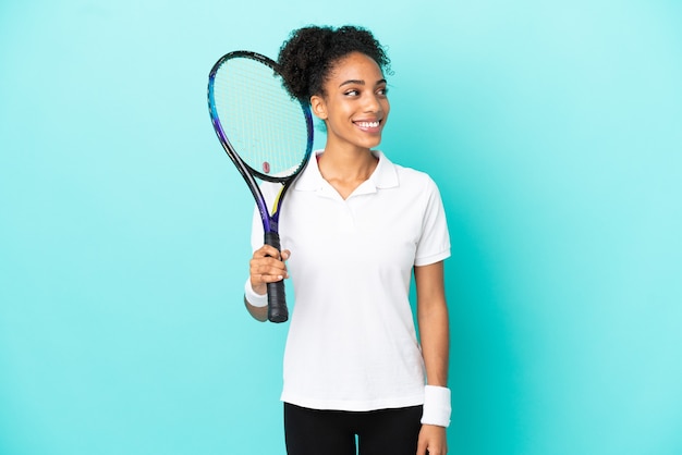 Młoda tenisistka na białym tle na niebieskim tle, patrząc w bok