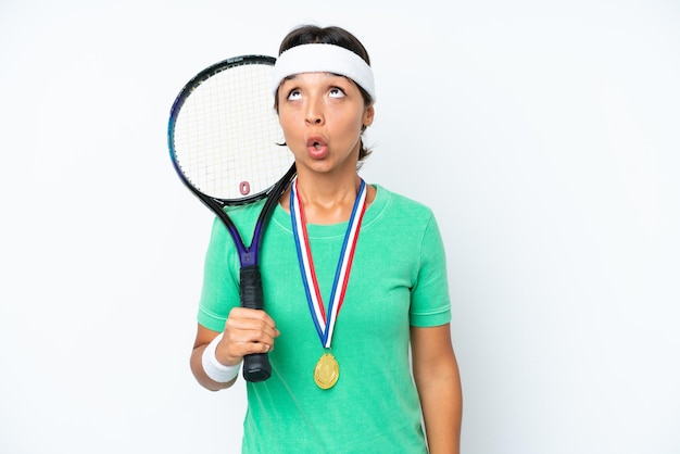 Młoda tenisistka odizolowana na białym tle patrzy w górę i z zaskoczonym wyrazem twarzy