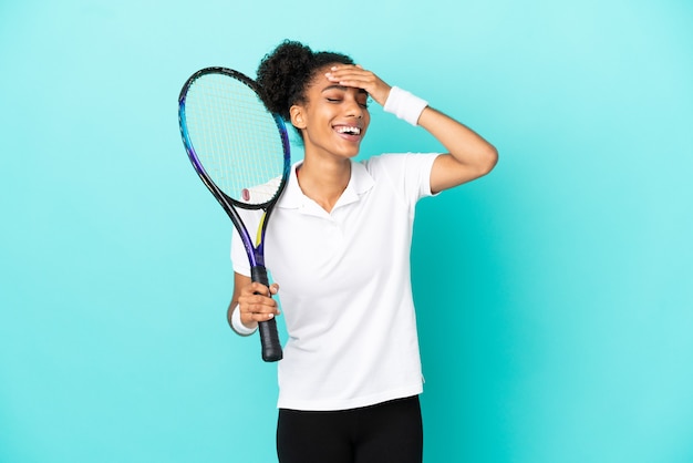 Młoda tenisistka odizolowana na niebieskim tle dużo się uśmiecha