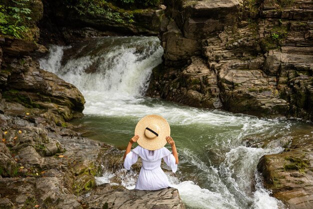 Młoda turystka siedząca przy górskim potoku lubi spędzać wolny czas na łonie natury