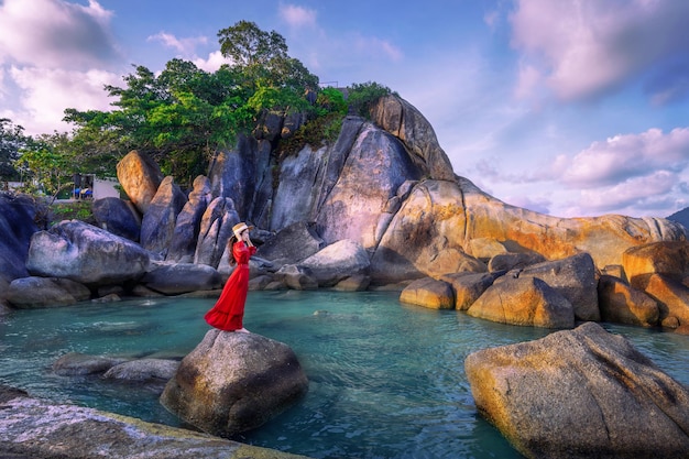 Młoda turystka w czerwonej sukience stojąca na Hin ta Hin Yai na wyspie Koh Samui