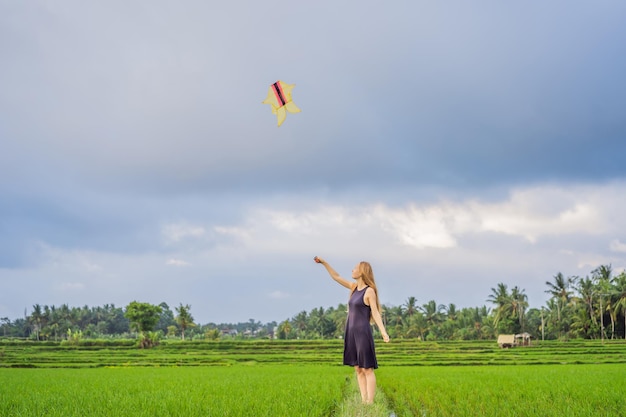 Młoda turystka wypuszcza latawiec na polu ryżowym na wyspie Ubud Bali w Indonezji