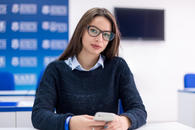 Młoda Uczennica Korzystająca Z Telefonu Komórkowego Podczas Przerwy W Klasie