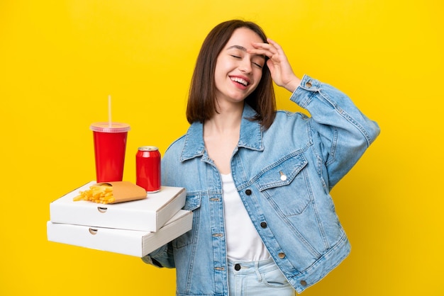 Młoda Ukrainka trzyma fast food na żółtym tle, uśmiechając się dużo