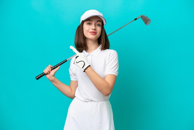 Młoda ukraińska golfistka kobieta odizolowana na niebieskim tle, wskazująca na bok, aby zaprezentować produkt