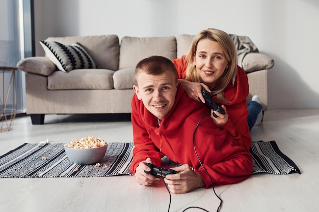 Młoda urocza para razem w domu grając w gry wideo w weekend i wakacje razem