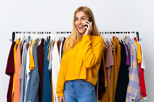 Młoda urugwajska blondynki kobieta w sklepie odzieżowym prowadzi rozmowę z telefonem komórkowym