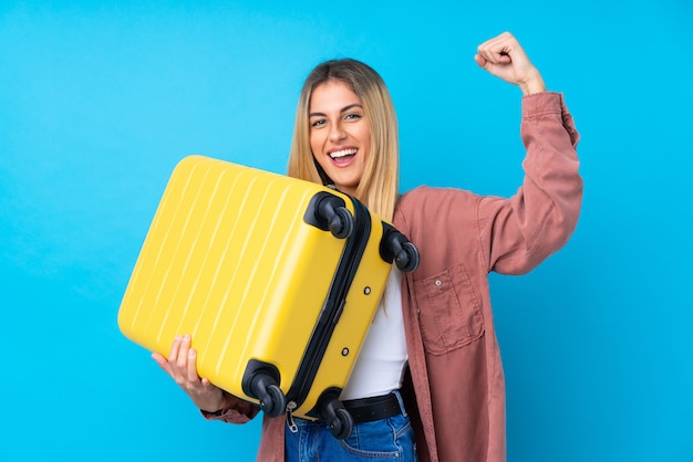 Młoda Urugwajska kobieta nad odosobnioną błękit ścianą w wakacje z podróży walizką