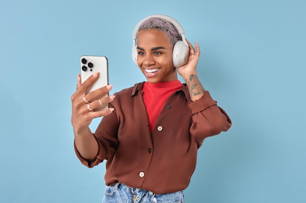 Zdjęcie młoda uśmiechnięta afroamerykańska kobieta używa słuchawek i stojaków telefonicznych w studiu