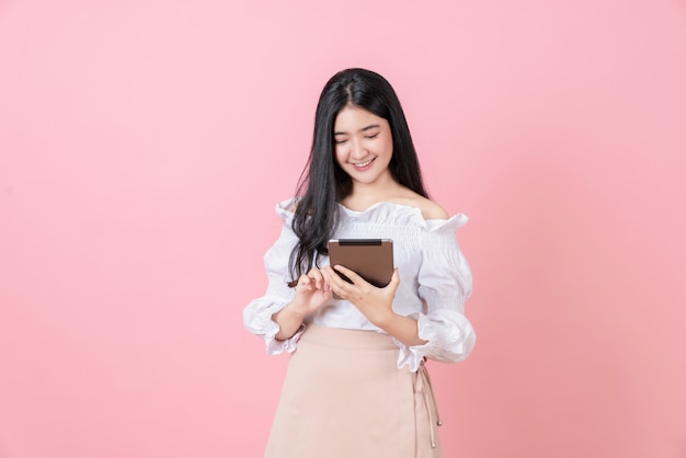 Młoda uśmiechnięta Azjatycka kobieta trzyma cyfrową pastylkę i patrzeje ekranizować
