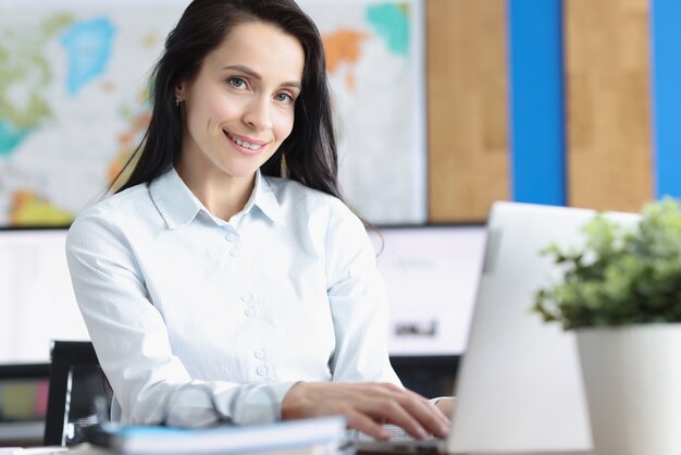 Młoda Uśmiechnięta Bizneswoman Siedzi Przy Laptopie W Biurze