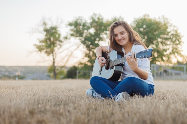 Młoda uśmiechnięta dziewczyna śpiewa na gitarze