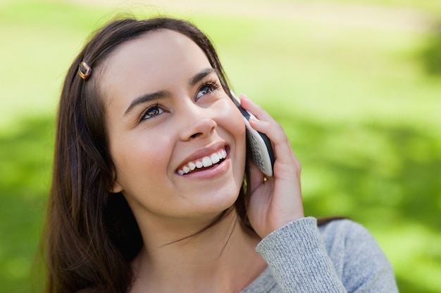 Młoda uśmiechnięta kobieta opowiada na telefonie podczas gdy przyglądający up