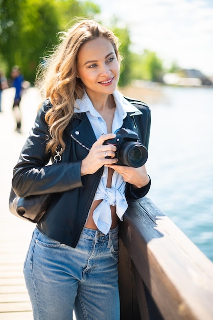 Młoda uśmiechnięta kobieta trzymająca kamerę odblaskową na zewnątrz