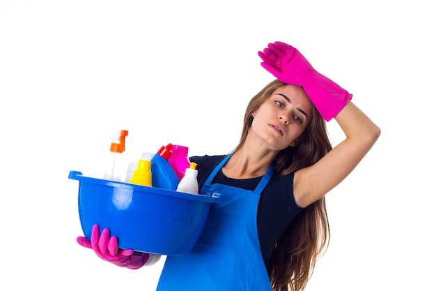 Młoda uśmiechnięta kobieta w rękawiczkach trzymająca rzeczy do czyszczenia w umywalce na białym tle w studio