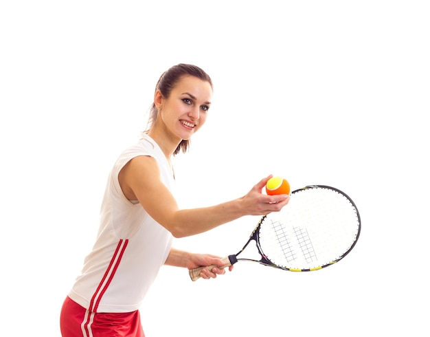 Młoda uśmiechnięta kobieta w sportowej koszuli i czerwonej spódnicy z kasztanowym kucykiem, trzymająca rakietę tenisową
