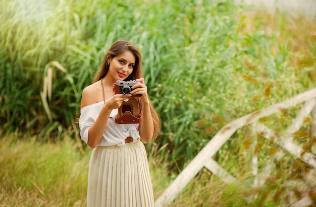 Młoda uśmiechnięta kobieta w ubrania w stylu vintage z aparatem retro