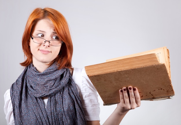 Młoda wątpiąca moda dziewczyna w okularach ze starą książką
