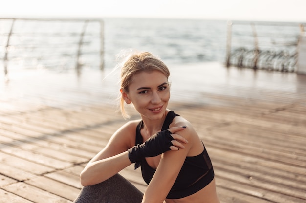 Młoda wesoła kobieta w sportowej na plaży o wschodzie słońca