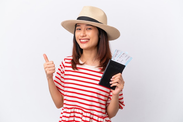 Młoda Wietnamka na białym tle na wakacjach trzyma paszport i samolot z kciukiem do góry