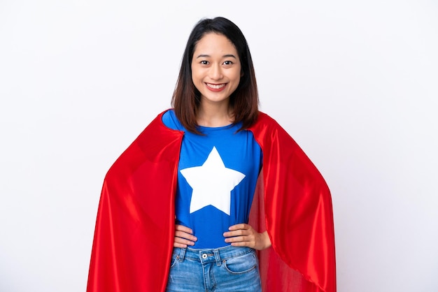 Młoda Wietnamka na białym tle w stroju superbohatera pozuje z rękami na biodrach i uśmiecha się